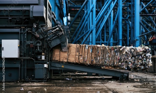 Industrial press compacts mixed recyclables into a large, dense bale