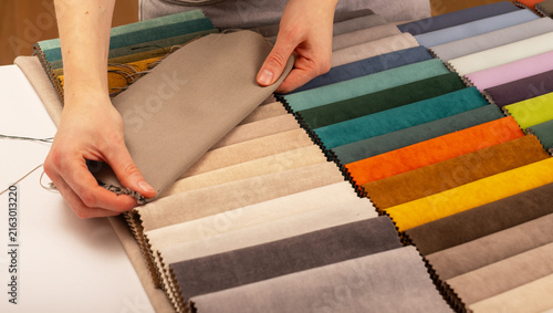 Upholstery fabric swatch catalog selection on workshop table. Interior designer choosing textile