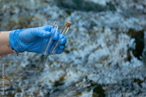 Fotografía person in blue gloves holding glass tube with water sample outdoors testing for