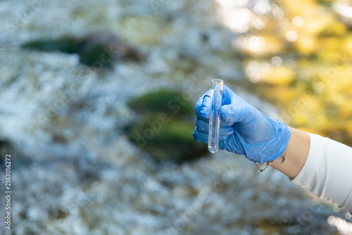 Foto person in blue gloves holding glass tube with water sample outdoors testing for