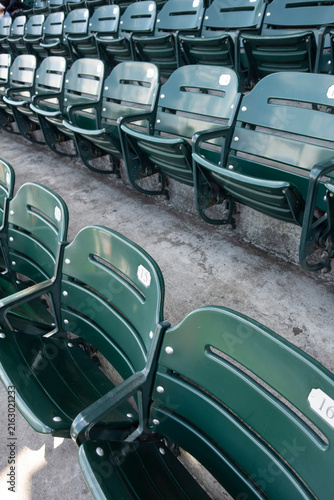 Фотография Rows of empty green stadium seats with numbered backs at an outdoor sports venue, creating a repeating geometric pattern and classic ballpark atmosphere