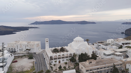 Aerial view of the Orthodox Metropolitan Cathedral in Fira with its white domes and arches overlooking the Aegean Sea in Fira, Greece.