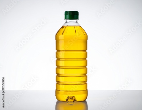 Plastic bottle of golden yellow cooking oil with green cap isolated on white background, vegetable oil container with reflection for food packaging design.
