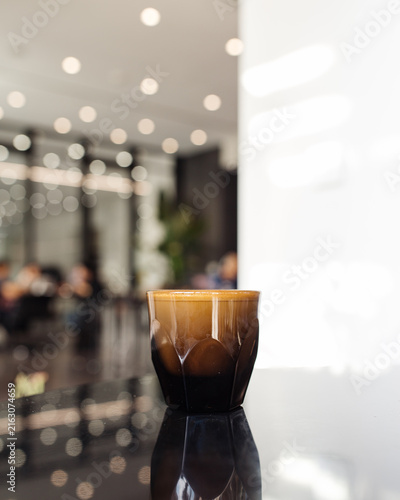 Foto Fresh espresso shot with crema in a faceted glass on a dark reflection table in