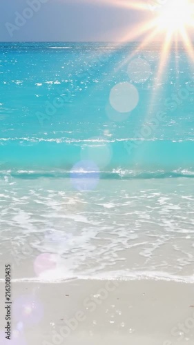Tropical beach waves washing onto white sand under bright sunshine with a relaxing ocean view