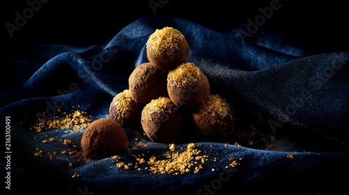 Chocolate truffles arranged in a pyramid on dark fabric background