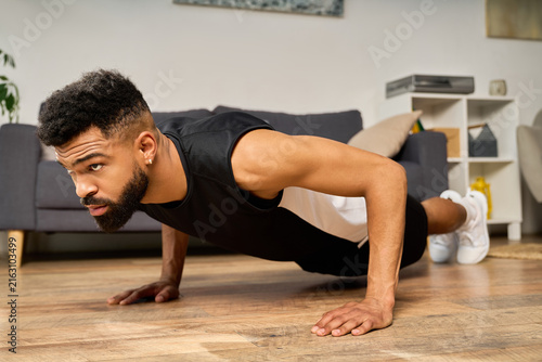 Fotografie A young African American man does push ups at home, showing determination and strength