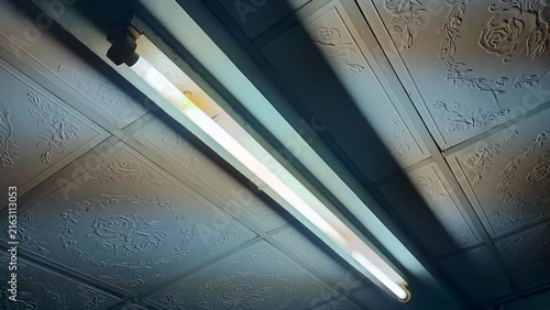 Obraz na plátne Glowing fluorescent light tube illuminating and white embossed rose patterned ce