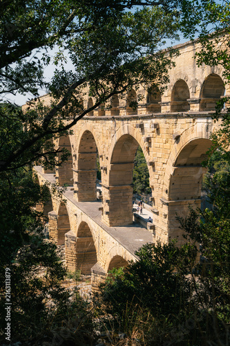 Quadro su tela Pont du Gard, aqueduc romain encadré par des arbres en été