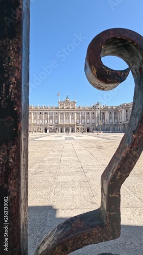 Madrid, Spain, 08-05-2026. Tracking shot moving through the iron fence to reveal the majestic facade of the Royal Palace of Madrid city, Spain (Europe), on a sunny day. Vertical video