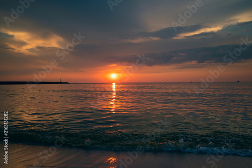 Beautiful colorful sunset in cloud sky at waving sea