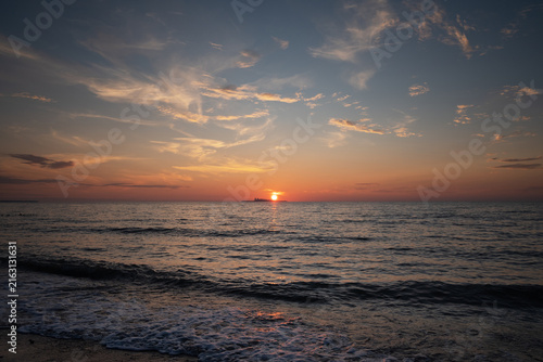 Beautiful colorful sunset in cloud sky at waving sea