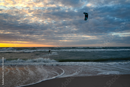 Kiteboarding sportsman rider with his kite in sea