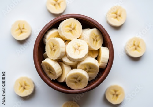 Fresh banana slices in a brown bowl isolated on white background