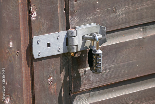 Combination lock on a shed door, locked, silver, grey, brown, shiplap wood