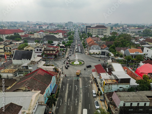 Aerial view of Tugu Yogyakarta Monument surrounded by city streets, traffic, and historic buildings under an overcast sky in Yogyakarta, Special Region of Yogyakarta, Indonesia.