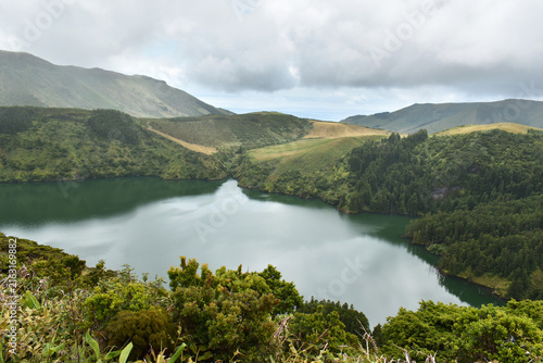Volcanic crater, Lagoa Funda surrounded by green vegetation on Flores Island, rain clouds, Azores