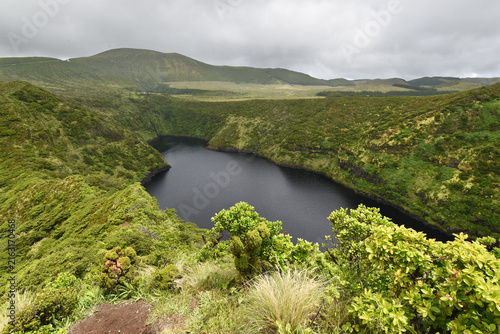 Volcanic crater, Lake Comprida surrounded by green vegetation on Flores Island, rain clouds, Azores