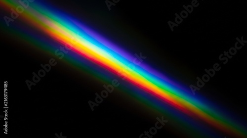 Vibrant spectrum of light shining diagonally across deep black background capturing brilliant colorful glowing refraction patterns