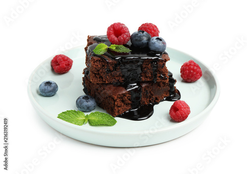 Pieces of delicious brownie with fresh berries, chocolate topping and mint isolated on white