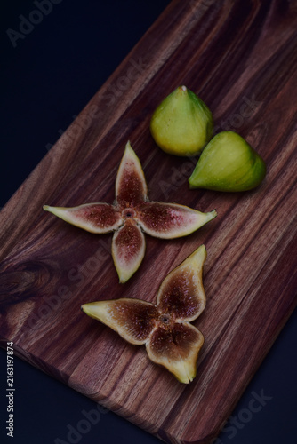 Fresh green figs whole and sliced on a wooden serving board