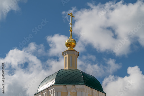 Konstfotografi Golden cross glimmers atop a church dome against a backdrop of fluffy clouds