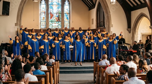 Diverse Choir in Blue and Gold Robes Singing Joyfully in a Church with Stained Glass Windows