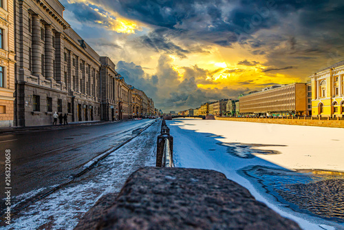 Snowy street glows under dramatic sunset skies