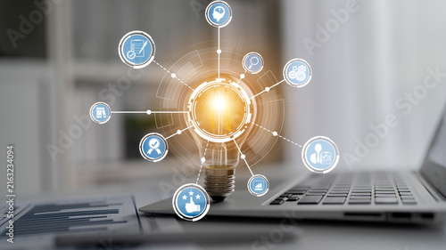 Obraz na płótnie A modern workspace featuring a light bulb representing innovation, connected to various digital icons symbolizing business strategies and productivity tools