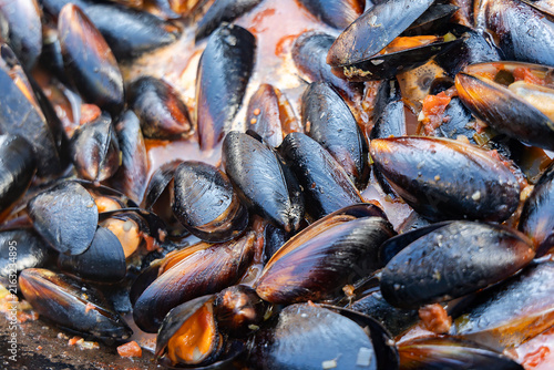 Mussels in tomato-garlic sauce on a roasting pan sclose-up. Freshly cooked shellfish.