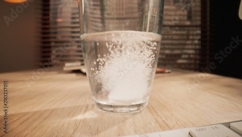 Fotografie Effervescent tablet dissolving in a glass of water creating bubbles and fizz
