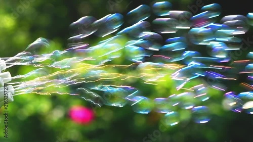 green toy bubble maker blowing iridescent soap bubbles into the air, creating a cheerful atmosphere celebrating summer recreation and childhood happiness outdoors