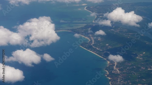 Aerial view of Phuket tropical island coastline with turquoise ocean water and white cumulus clouds daytime landscape high angle shot from airplane