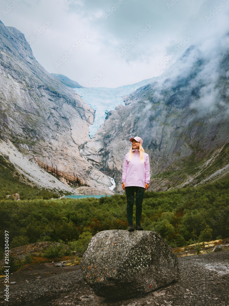 Obraz premium Woman travel solo in Norway sightseeing Briksdalsbreen glacier view female tourist hiking in mountains active summer vacations healthy lifestyle tour explore Stryn, freedom candid emotion coolcation