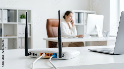 Wireless router on a white office desk with a blurred person working in the background.
