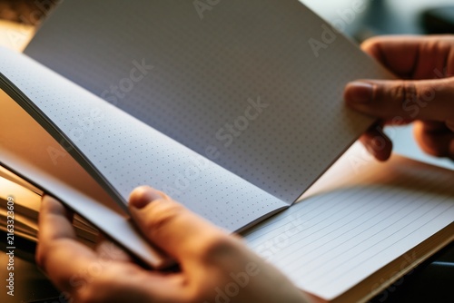 Hand holding an open notebook with lined pages.