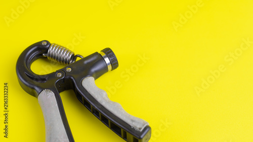 Obraz na płótnie Close up of adjustable hand gripper on bright yellow background with copy space