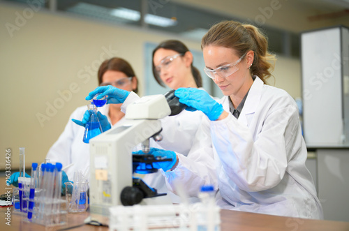 Foto Three female scientists in a lab conducting experiments with blue liquid and a m