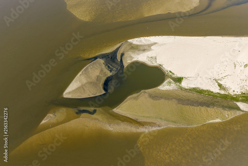 Aerial view of exposed sandbanks and low water levels in a river, showing sediment patterns and shallow water channels in Poland.