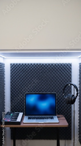 Soundproof recording studio booth with a laptop template and a midi keyboard