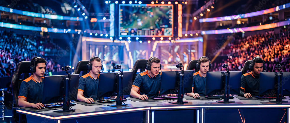 Fototapeta premium Professional esports team competing in high-stakes gaming tournament with live audience and stadium production