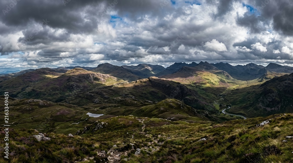 Fototapeta premium Panoramic Dramatic Mountain Landscape with Rolling Green Hills and Stormy Clouds over a Highland Valley
