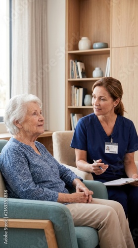 Caring Nurse Discusses Seniors Well-being With Elderly Woman In Comfortable Living Room