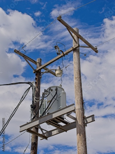 Konstfotografi Electric transformer mounted between two wooden power poles set against blue sky
