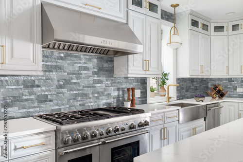 Bild auf Leinwand Modern white kitchen interior with grey stone tile backsplash and steel range