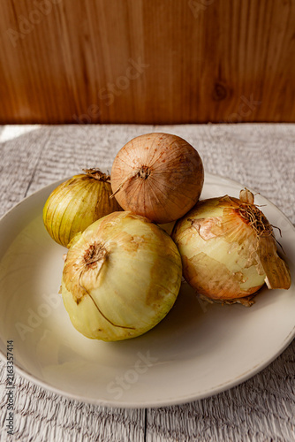 Fresh whole unpeeled onions with papery brown skins. Perfect rustic ingredient photo for culinary designs, food blogs, or cooking concepts.