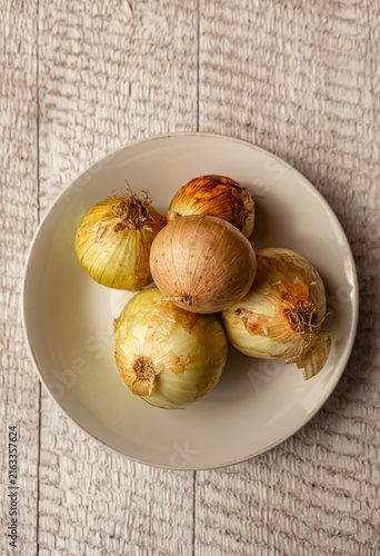 Fresh whole unpeeled onions with papery brown skins. Perfect rustic ingredient photo for culinary designs, food blogs, or cooking concepts.