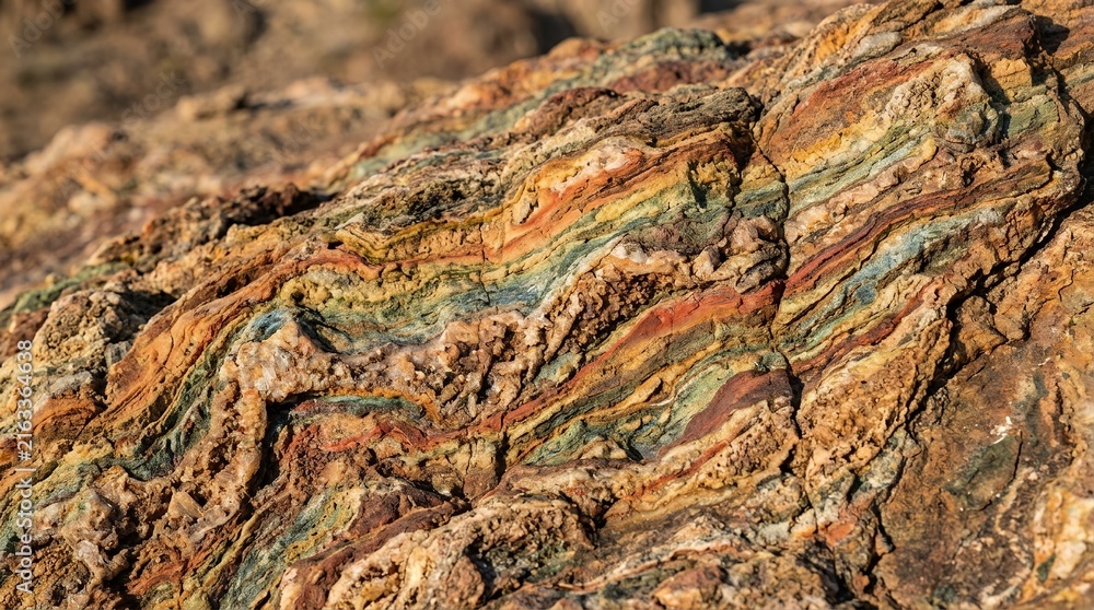 Fototapeta premium Vibrant Colorful Mineral Deposits in Layered Rock Formation of Ancient Geological Sedimentary Stone Surface Texture