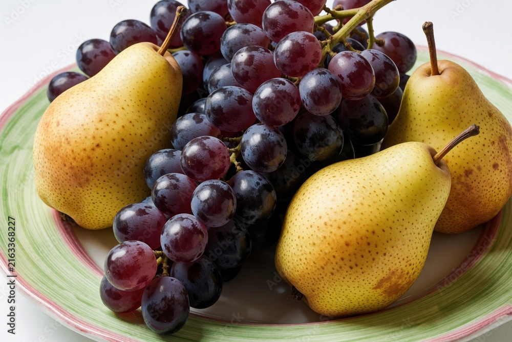 Naklejka premium Ripe pears and dark grapes are arranged on a decorative plate. Fresh healthy fruits offer a sweet natural snack perfect for any meal or dessert.
