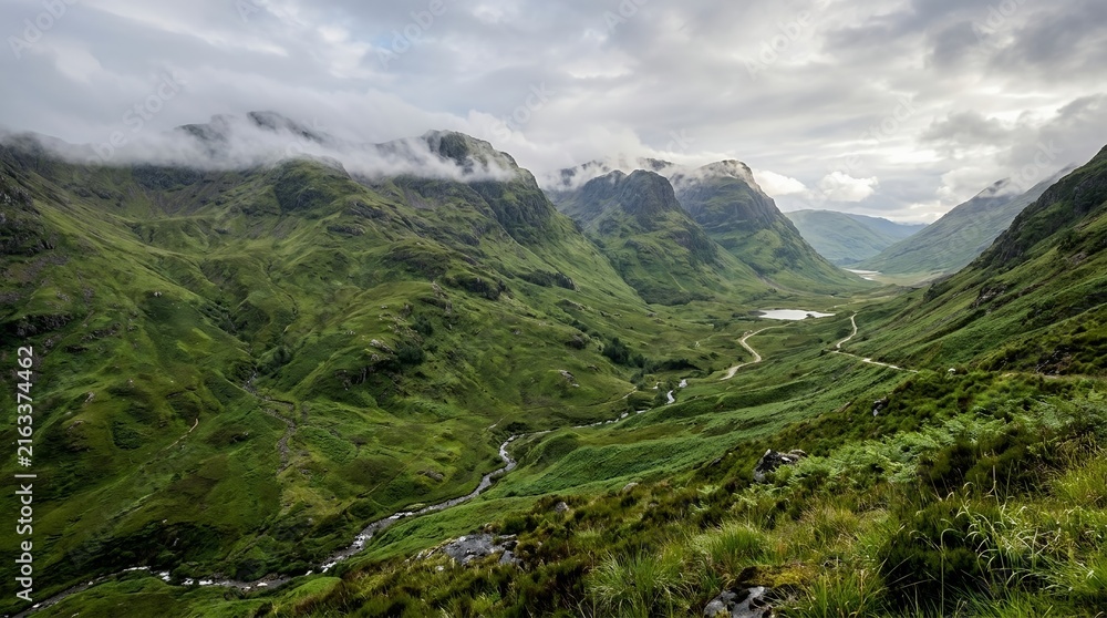 Fototapeta premium Stunning Lush Green Mountain Valley with Winding River Under Dramatic Cloudy Sky in a Wilderness Landscape